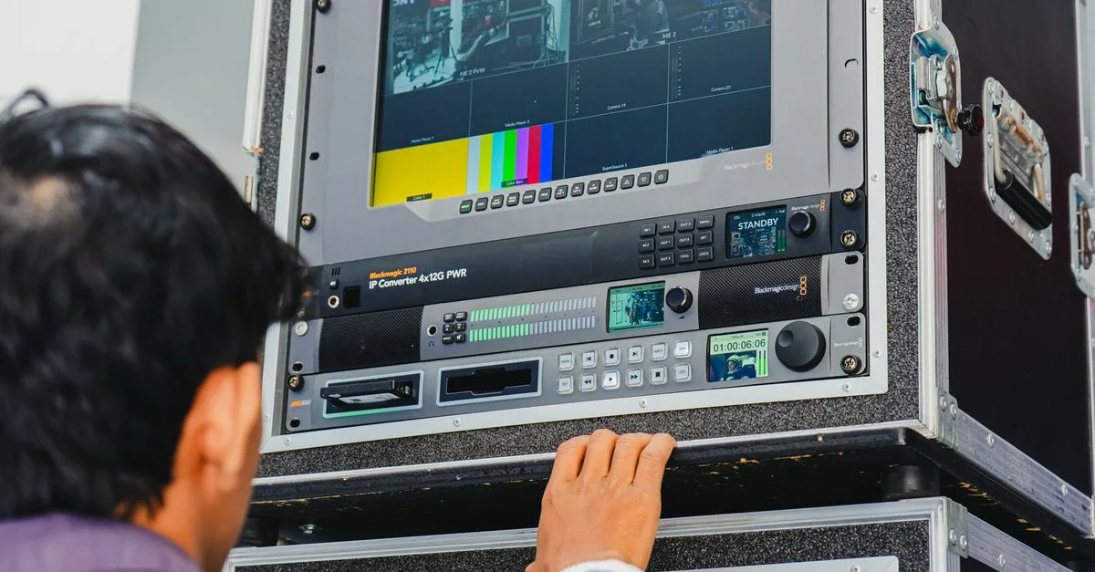 A technician manages professional broadcasting equipment in a control room setting.