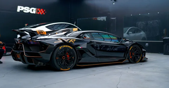 Black sports car with aerodynamic design in a sleek modern garage environment.