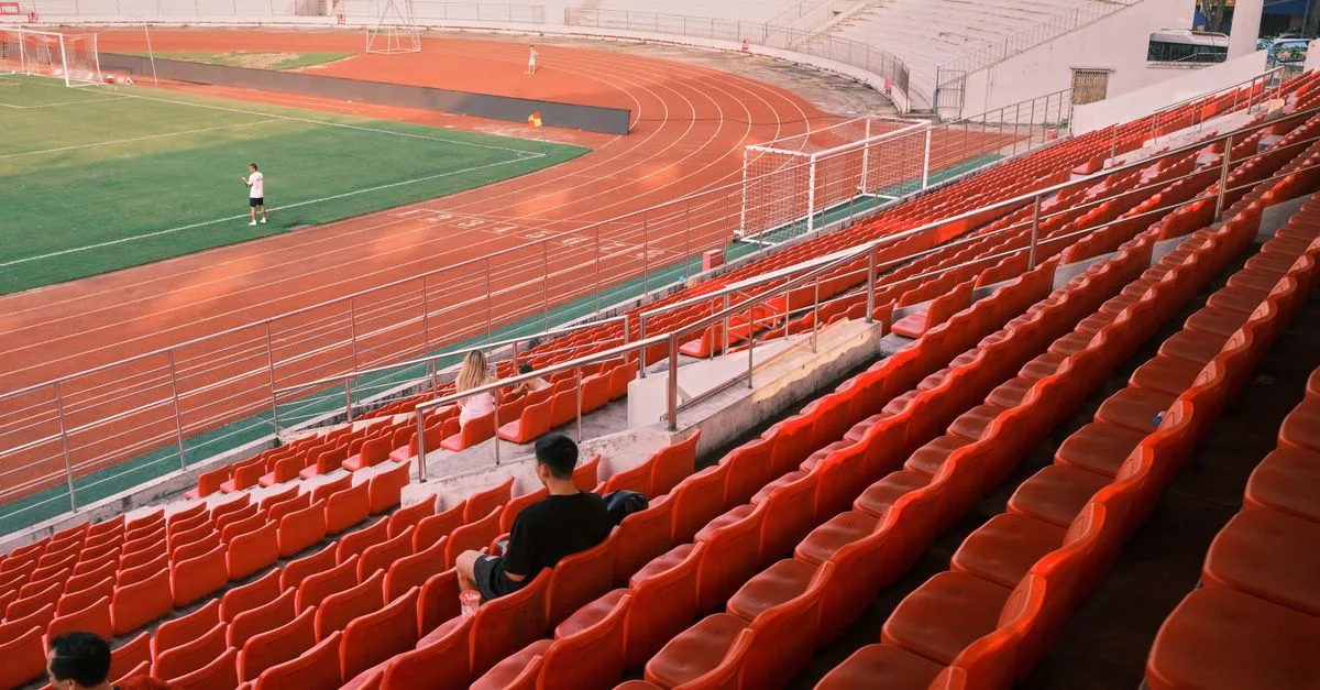 Quiet football stadium in Hải Phòng, Vietnam, with red seats and a lush green field.