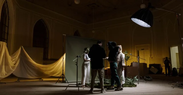 A photography crew setting up lighting and background indoors for a photo shoot.