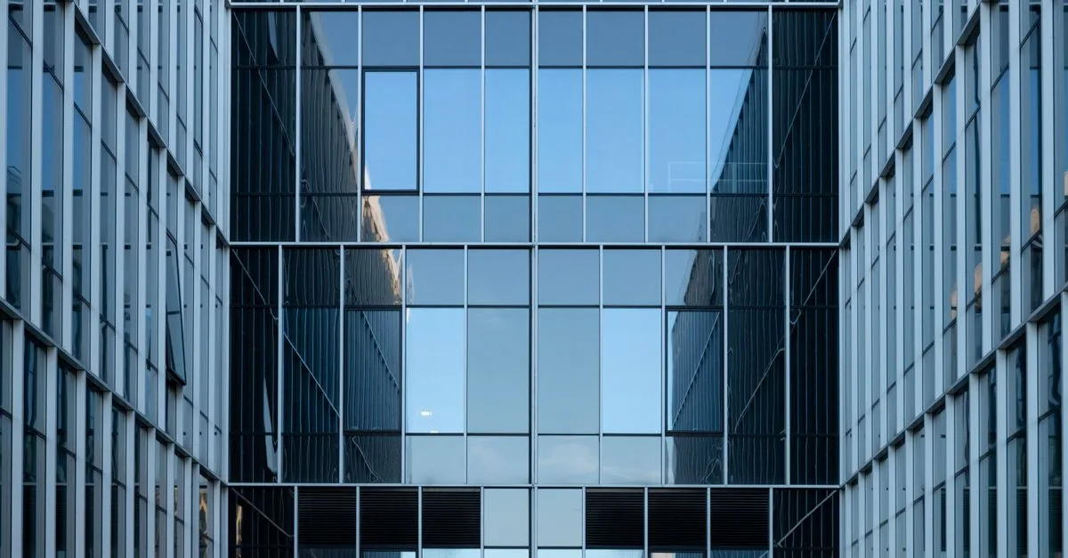 Contemporary building facade with reflective glass windows in an urban environment.