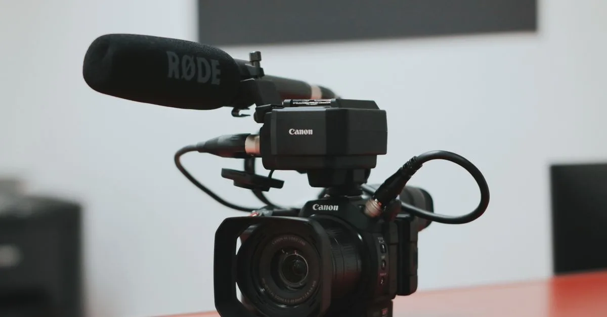 Close-up of a professional video camera setup with Rode microphone on a desk.