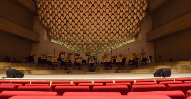 Elegant concert hall interior with empty seats and stage, ready for performance.