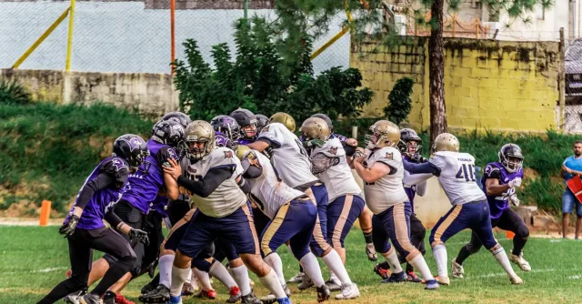 Football players in colorful uniforms compete during a sunny outdoor game.
