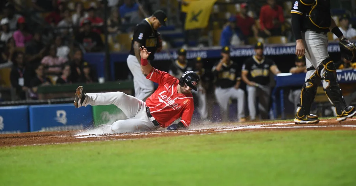 Sliding baseball player during an exciting game in Santo Domingo stadium.