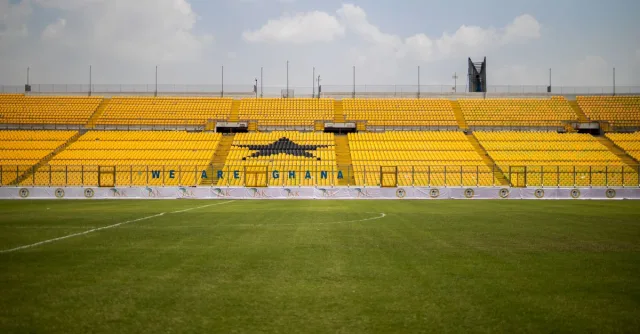 Stadium with bright yellow seats and green lawn under a blue sky in Ghana. Ideal for sports events.