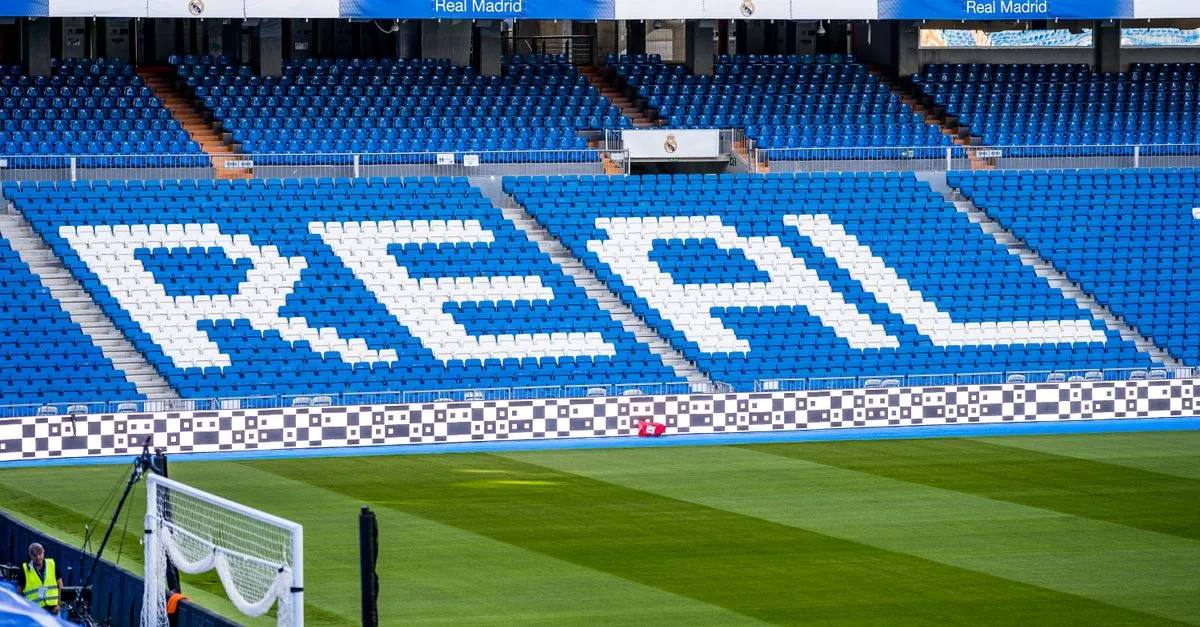 Empty seating area in Real Madrid's stadium with 'REAL' prominently displayed in white.