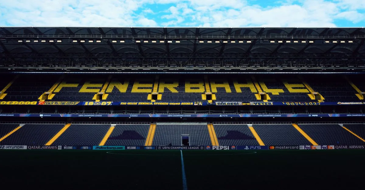 Interior view of Fenerbahçe Stadium with empty seats and bright signage.