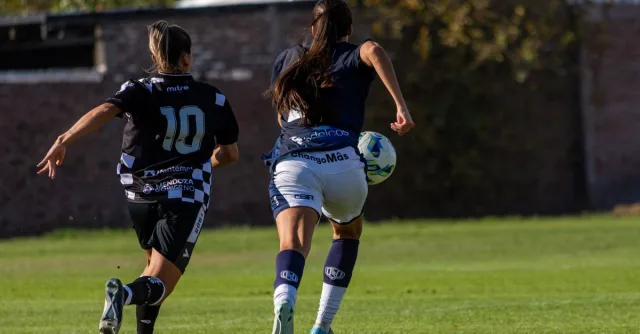 Exciting capture of two female soccer players in action on the field during a sunny day.