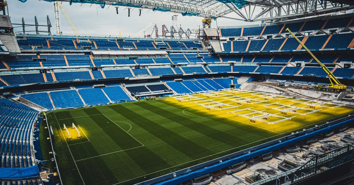 Aerial view of ongoing renovation at Santiago Bernabéu Stadium in Madrid, showcasing construction and vibrant seating arrangement.