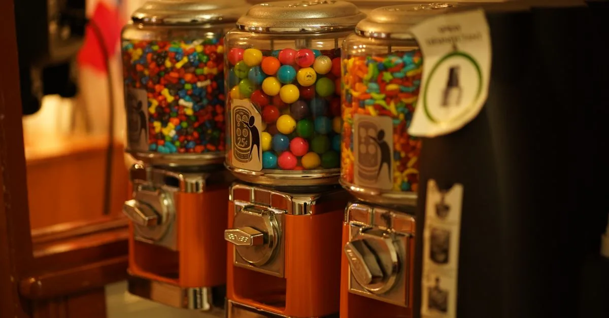 Close-up of colorful candy displayed in vintage vending machines indoors.