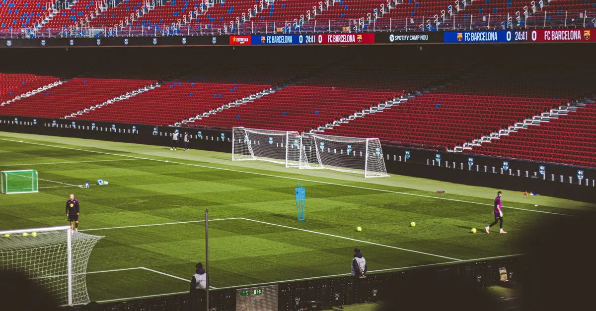 Soccer practice at a famous stadium with vibrant red seating and green field.
