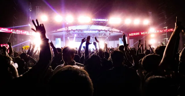 Energetic crowd enjoying a live concert under bright stage lights in Guwahati, India.