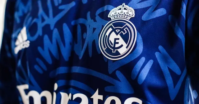 Close-up view of a blue Real Madrid soccer jersey featuring the team's logo and design elements.