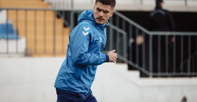 Focused football player warming up on the field in Baku, Azerbaijan, showcasing athletic determination.