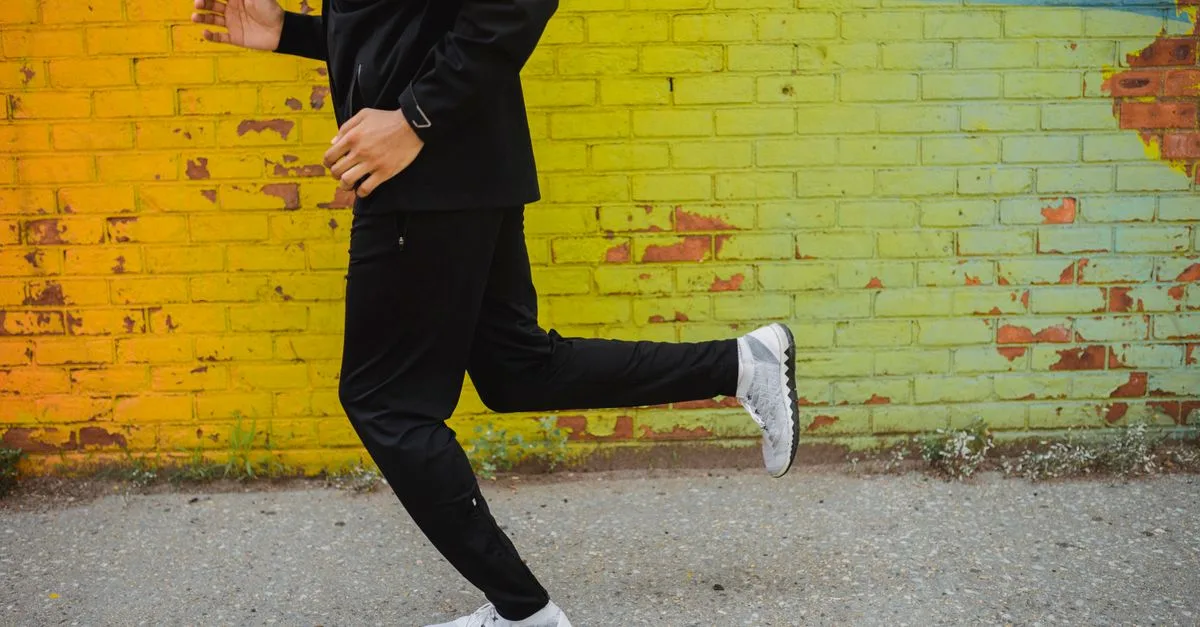 Runner jogging along a colorful urban brick wall in casual sportswear.