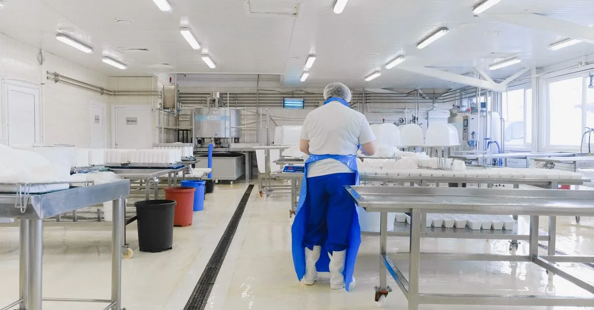 A person wearing protective clothing working in a bright, sterile laboratory environment.