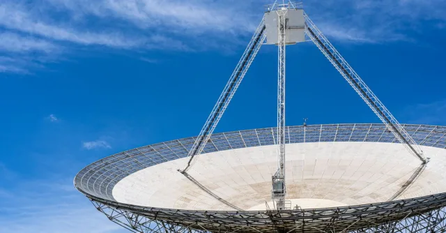 A large satellite dish with a clear blue sky in the background, showcasing modern communication technology.