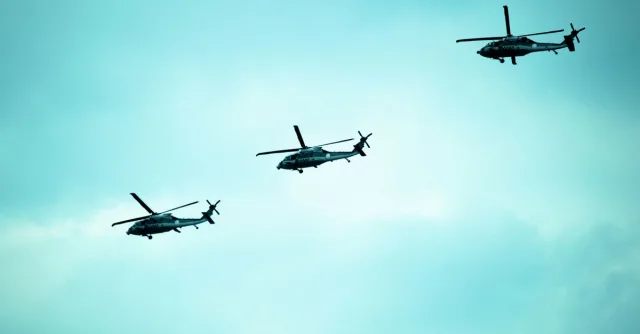 Three military helicopters flying in formation against a blue sky in Mexico City.