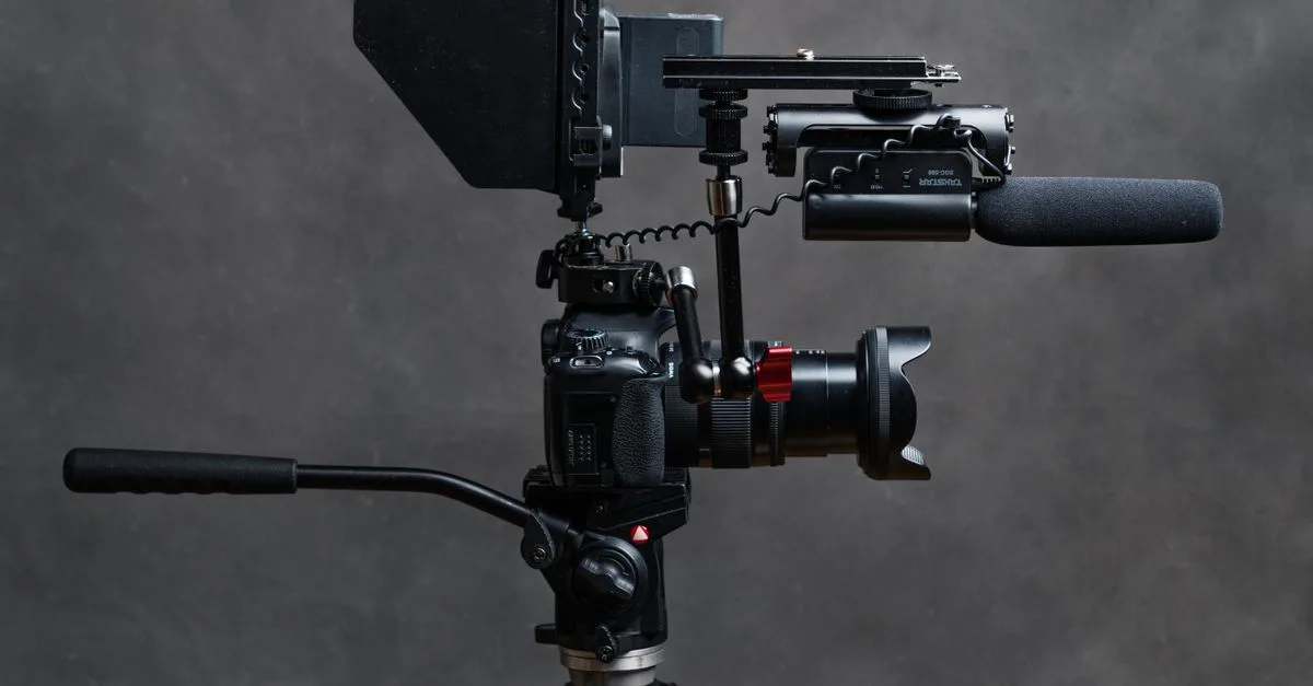 Close-up studio shot of a DSLR camera with video accessories including a microphone and tripod.