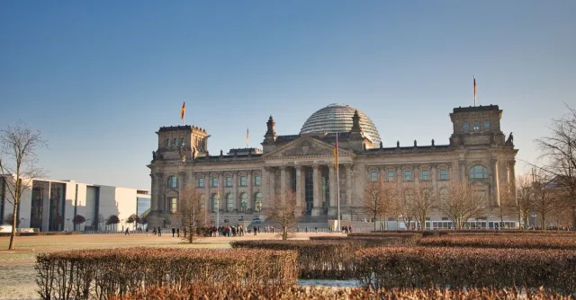 A view of the historic Reichstag building in Berlin, Germany, under a clear winter sky.