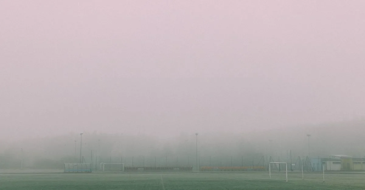 A foggy football field with goals visible, creating a serene and moody winter atmosphere.