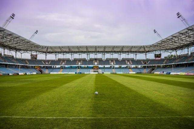 A wide view of a professional football stadium pitch during an evening match.