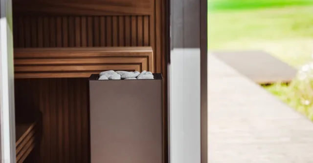 Contemporary outdoor sauna featuring wood panels and an electric heater with stones.