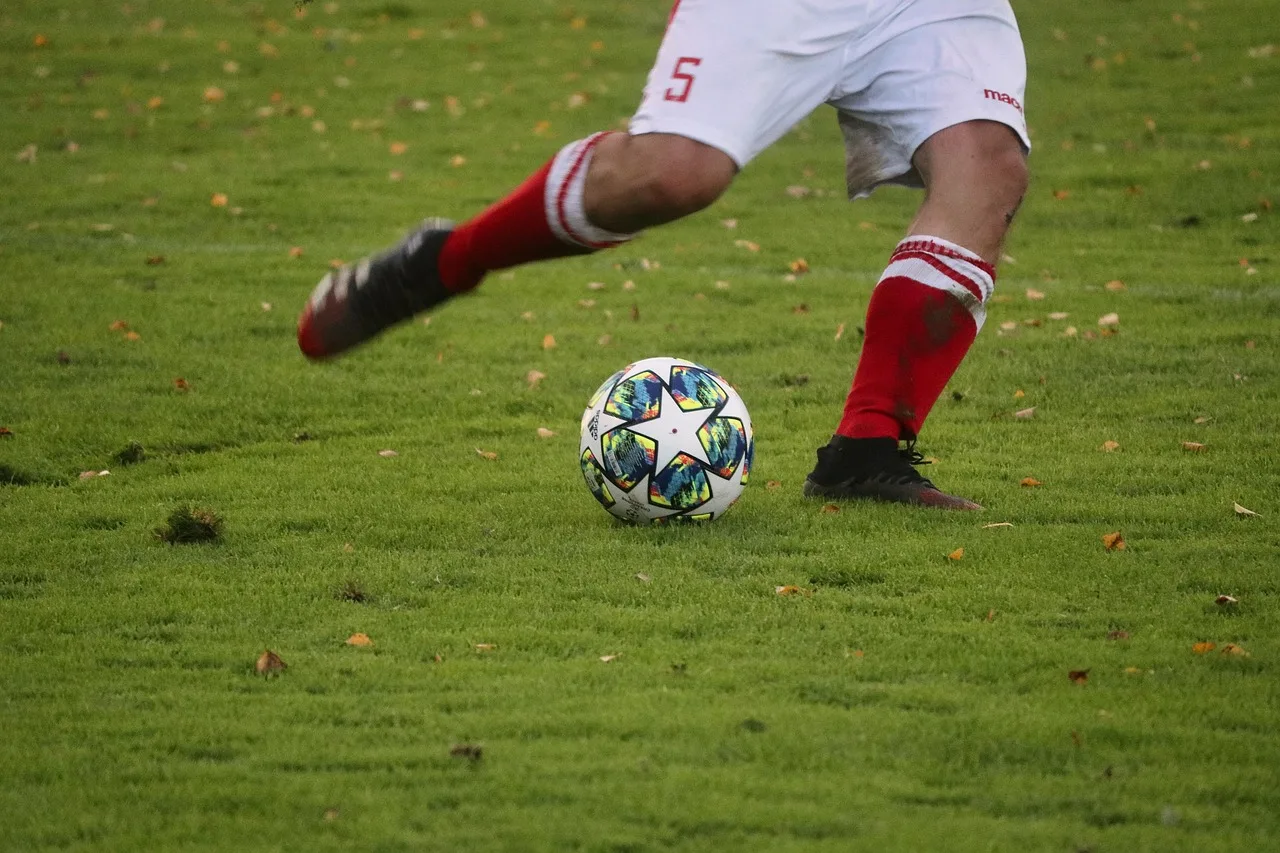 A professional football stadium during an evening match with bright floodlights.