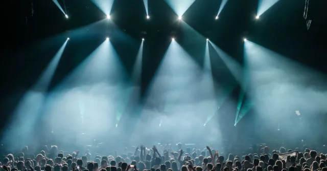 A dynamic concert scene with a large crowd enjoying vibrant stage lighting and a lively atmosphere.