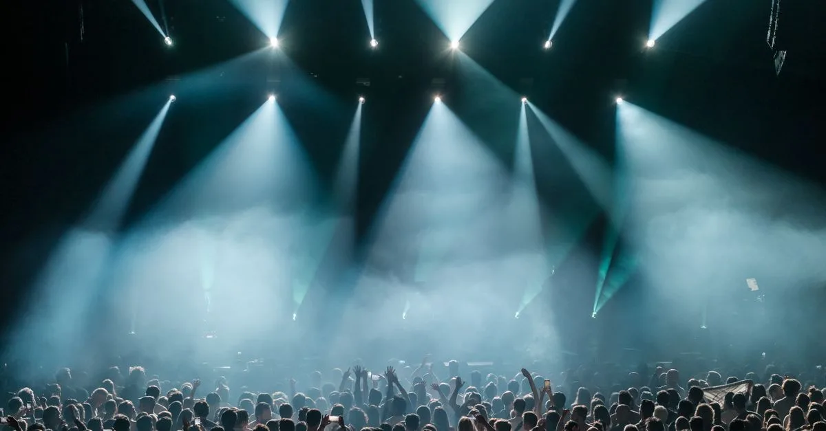 A dynamic concert scene with a large crowd enjoying vibrant stage lighting and a lively atmosphere.