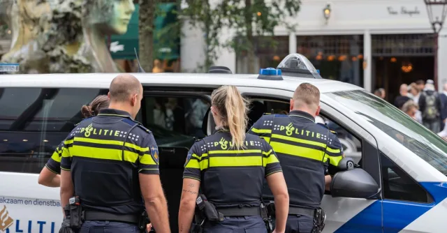 Police officers in uniform inspecting a vehicle on a busy city street, ensuring public safety.