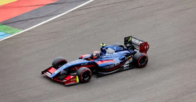 Blue race car speeding on a track with colorful markings, showcasing motorsport action.