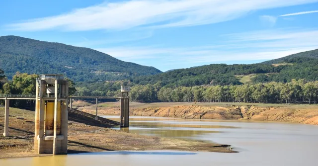 A striking view of a drought-affected reservoir surrounded by mountains and forest.
