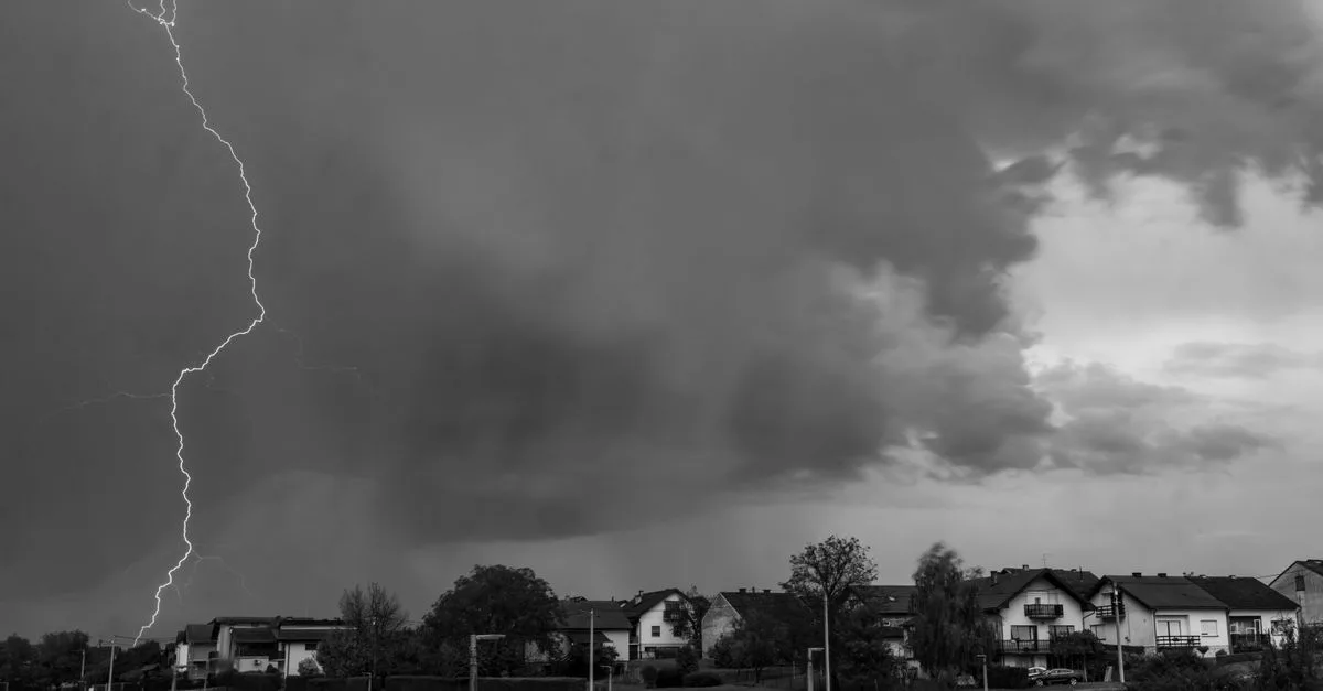 Monochrome image capturing a dramatic lightning strike during a thunderstorm over a neighborhood.