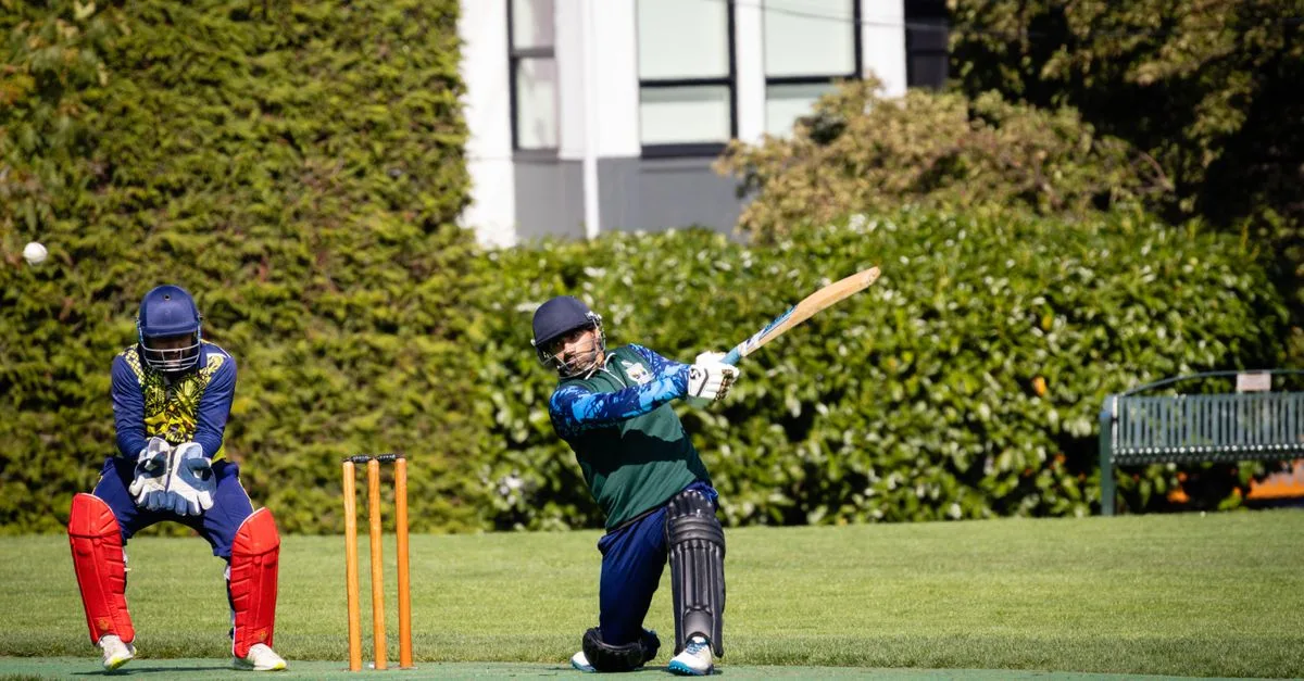 Cricketers in action during a vibrant outdoor cricket match in Victoria, BC.
