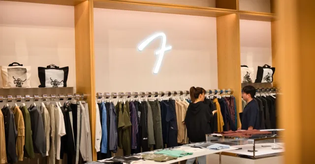 Interior of a stylish clothing store in Tokyo featuring two shoppers browsing modern apparel.