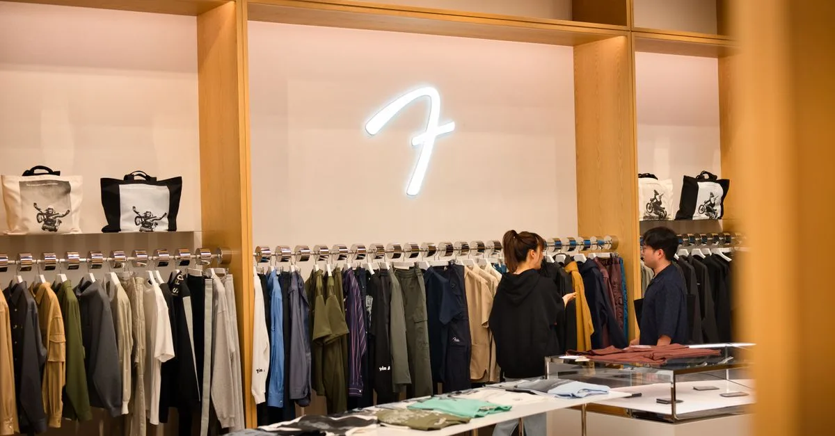 Interior of a stylish clothing store in Tokyo featuring two shoppers browsing modern apparel.