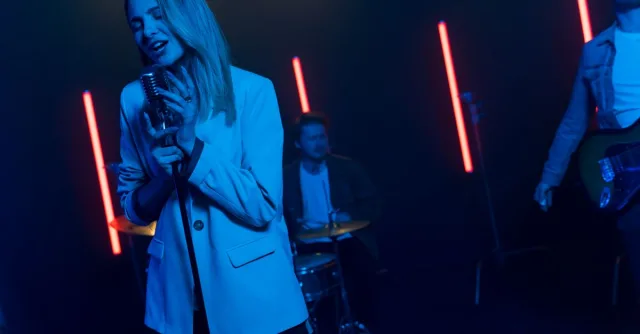 A vibrant band performance with singers and musicians under dramatic neon lighting on stage.