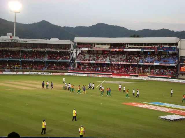 A cricket stadium during a day match with a clear pitch.
