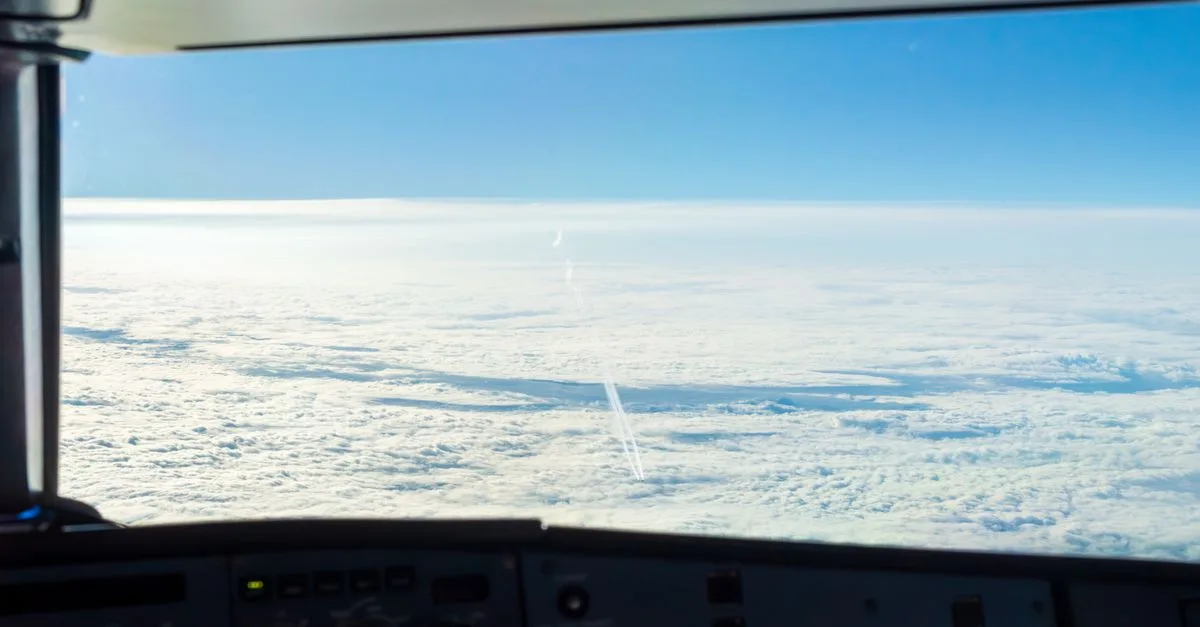 Experience the serene beauty of fluffy clouds from an airplane cockpit high above the sky.