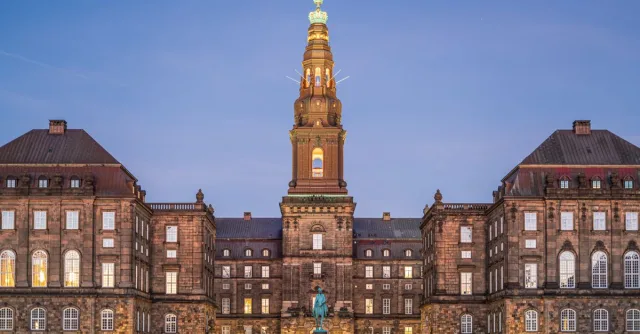 Christiansborg Palace in Copenhagen beautifully illuminated at dusk, showcasing its historic architecture.