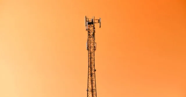 Radio mast silhouetted against a vibrant orange sky in Adana, Türkiye.