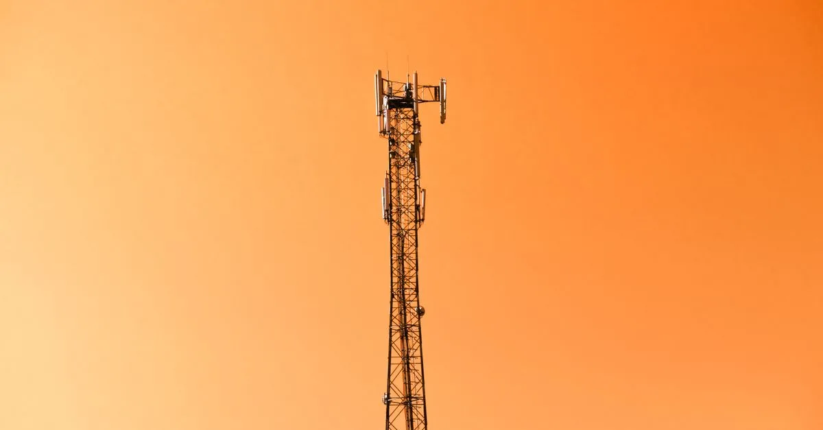 Radio mast silhouetted against a vibrant orange sky in Adana, Türkiye.