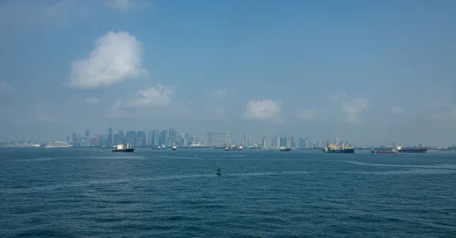 View of Singapore skyline with vessels navigating the sea under a clear blue sky.