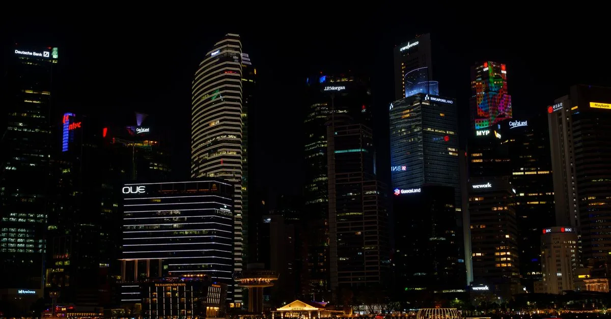 Stunning view of Singapore's skyline at night, featuring illuminated skyscrapers reflecting on the water.
