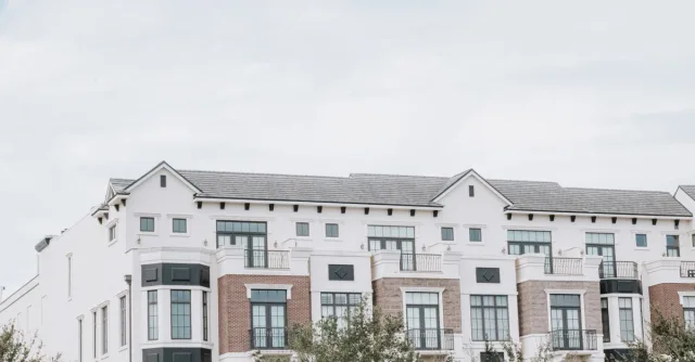 A stylish, multi-story luxury apartment building with a contemporary facade against a clear sky.