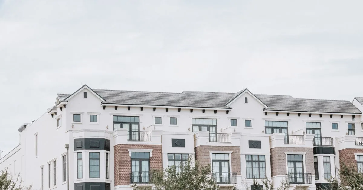 A stylish, multi-story luxury apartment building with a contemporary facade against a clear sky.