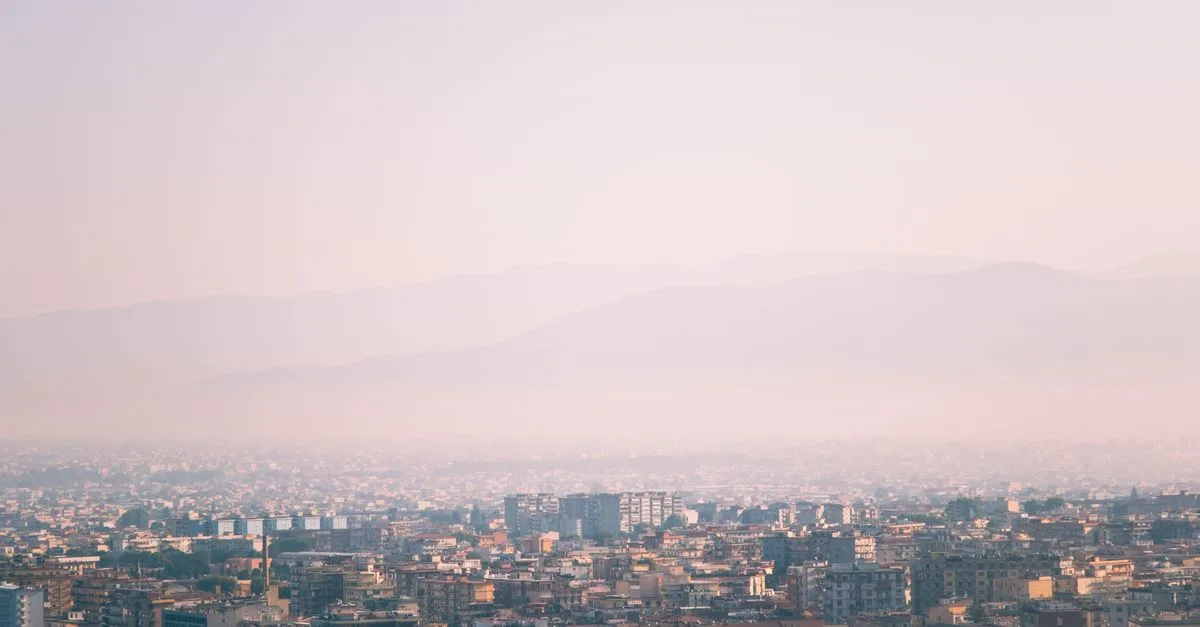 A hazy cityscape view during a misty morning with soft light and urban skyline.
