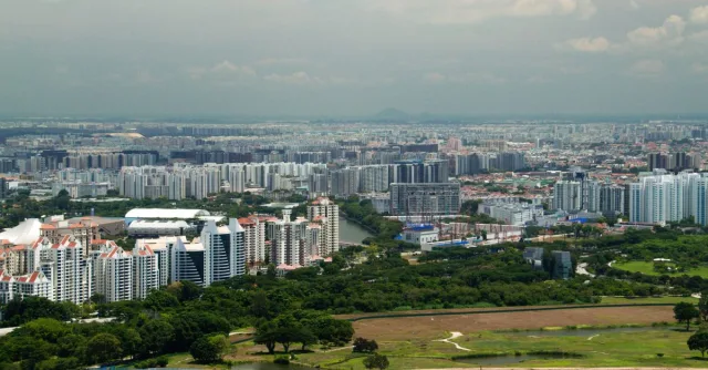 A panoramic aerial view of Singapore showcasing dense urban buildings amidst lush greenery.